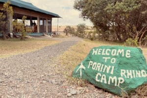 Entrance to Porini Rhino Camp in Kenya with welcome sign and safari tent lodge
