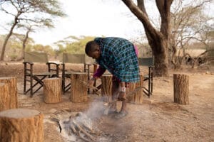 Maasai man tending campfire at safari campsit
