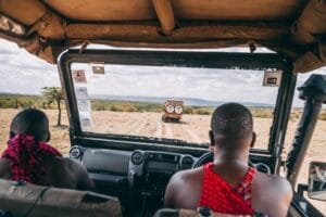 View from safari vehicle with Maasai guides driving through Kenyan savannah"