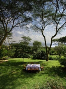Outdoor dining table set in lush green garden with scenic view
