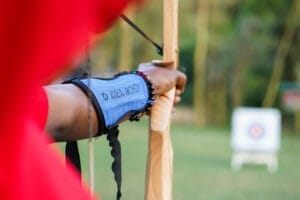 Close-up of person practising archery with bow and target in the background