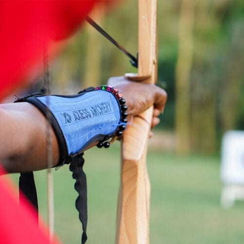 Close-up of person practising archery with bow and target in the background