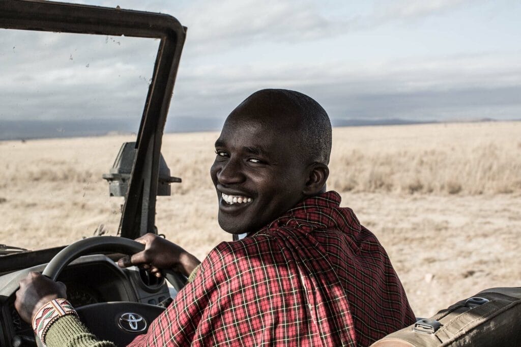 Smiling safari guide driving a Toyota 4x4 jeep in African savanna