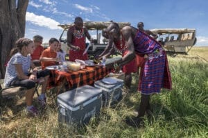 Family enjoying bush picnic on safari with Maasai guides in Kenya