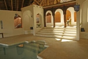 Luxury indoor pool and lounge area with traditional Swahili architecture at a boutique safari lodge in Kenya