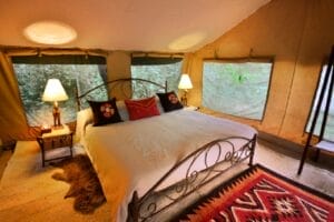 Spacious safari tent bedroom with king-size bed and traditional Maasai decor in Kenya wilderness