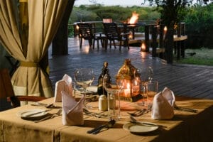 Romantic safari lodge dining setup with candlelit table and outdoor firepit in the African wilderness