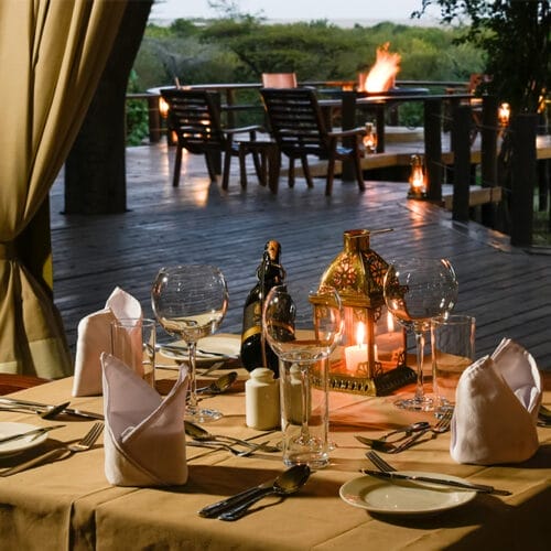 jubileegallery3 | Gamewatchers Safaris Romantic safari lodge dining setup with candlelit table and outdoor firepit in the African wilderness