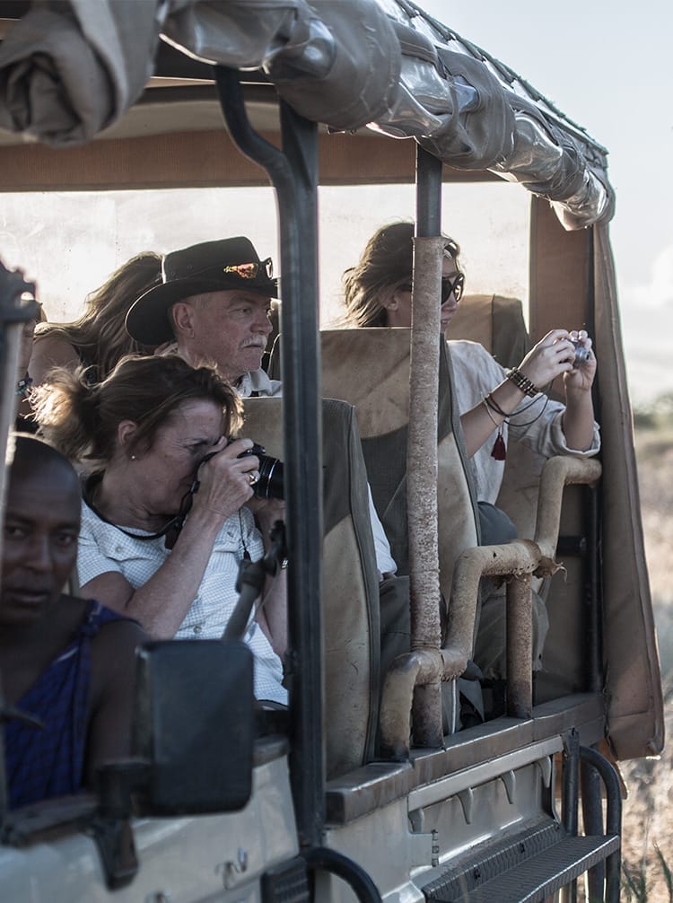 Tourists taking wildlife photos from safari vehicle during African game drive