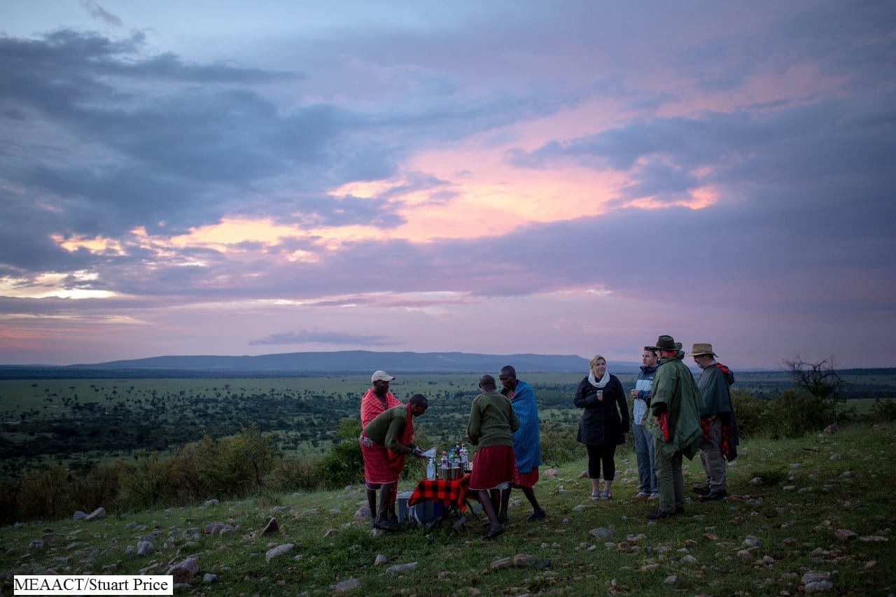 Tourists and guides at a sunset safari gathering in the savannah