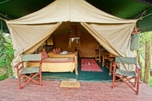 Luxury safari tent accommodation with double bed and outdoor seating in Kenya