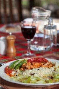 Delicious safari lodge meal with fresh vegetables, couscous, and wine in Kenya