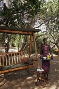 Local Maasai staff serving breakfast outdoors at a safari lodge in Kenya