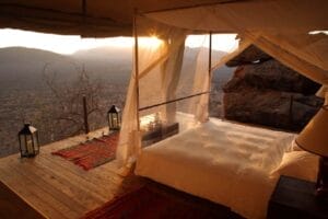 Luxury safari tent bedroom with canopy bed and panoramic mountain views at sunrise in Kenya