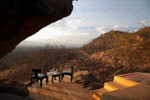 Private outdoor deck with chairs and drinks overlooking mountains and savannah in Kenya safari lodge