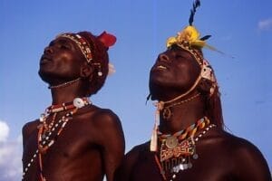 Two Maasai men in traditional attire with beadwork and feathered headpieces in Kenya