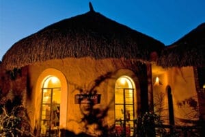 Thatched-roof safari lodge gift shop illuminated at night in Kenya