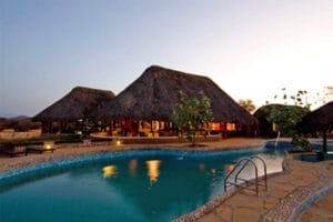 Luxury safari lodge with thatched roof cottages and swimming pool in Kenya