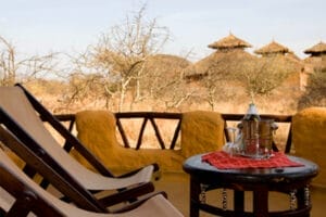 Safari lodge terrace with traditional thatched huts and outdoor seating in Kenya