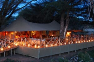 Luxury safari tented camp with lantern-lit deck at dusk in Kenya
