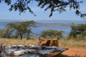 Outdoor dining table set with glassware overlooking Lake Nakuru in Kenya