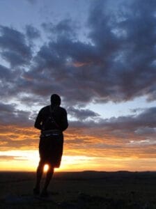 Silhouette of Maasai warrior watching sunrise over African savannah landscape