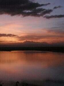 Serene African sunset over lake with dramatic clouds reflecting on water in Kenya safari landscape