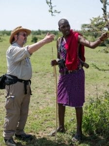 Safari guide with tourist exploring Maasai Mara wilderness in Kenya