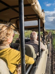 Tourists on a guided safari game drive vehicle exploring the African savannah
