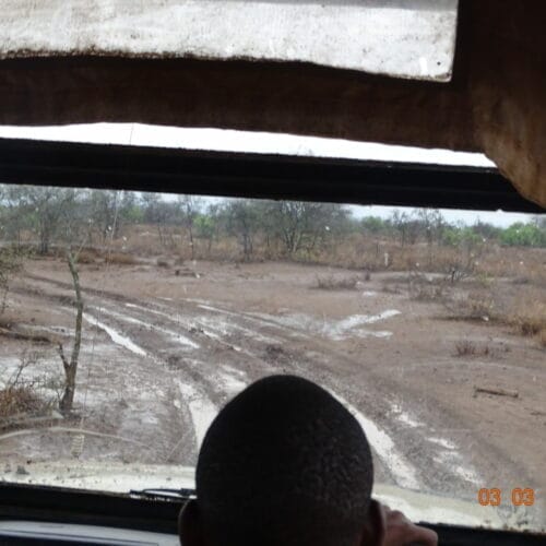 View from a safari vehicle window showing muddy tracks and dry landscape