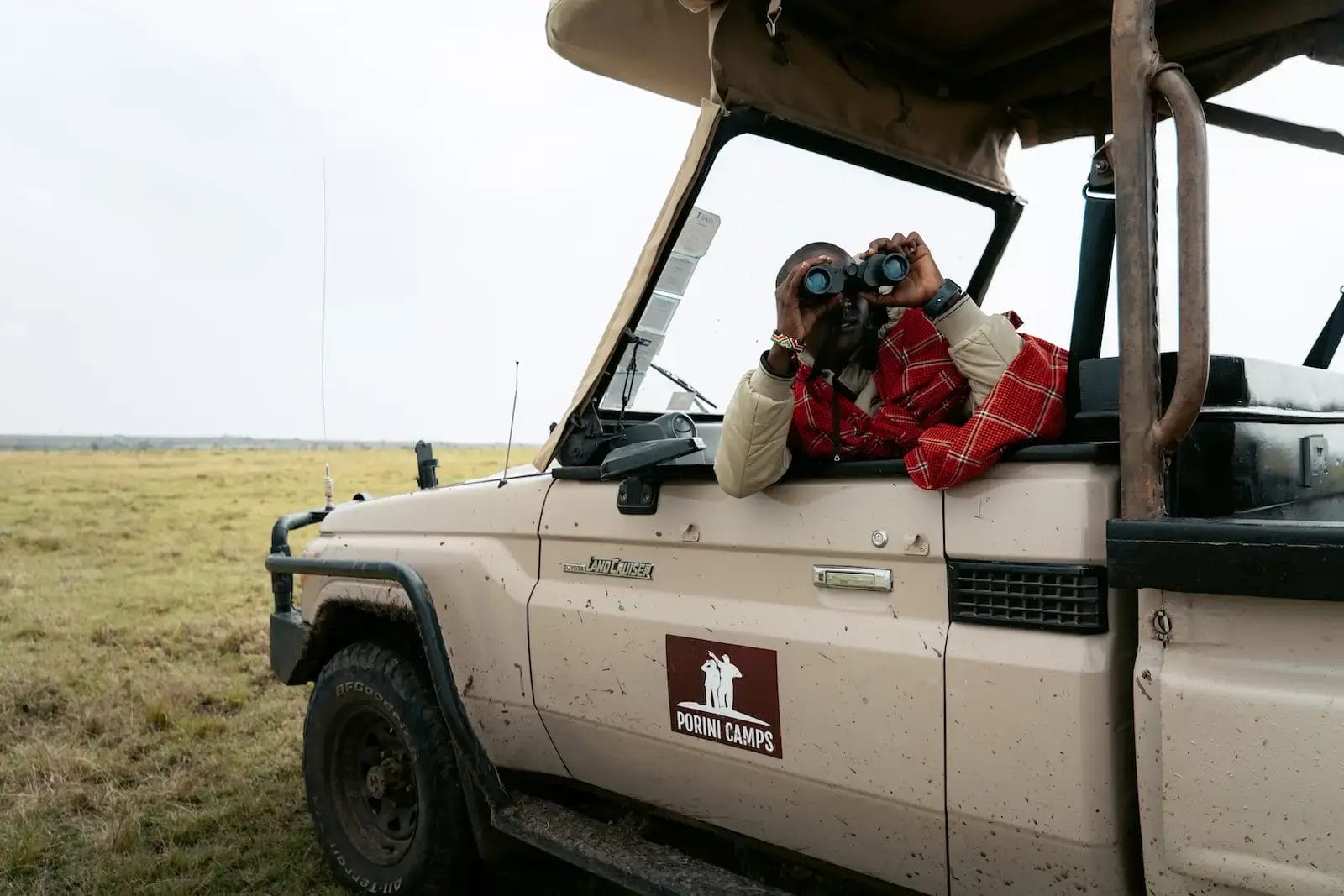 A professional Maasai Guide looks through binoculars at the wildlife scene taken from Porini Lion Camp in Olare Motorogi Conservancy in Kenya. Photo credit Celine & Sacha