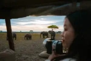 A lady holding professional camera overlooking a classic wildlife photography scene taken from Porini Safari Cottages in Ol Kinyei Conservancy in Kenya. Photo credit Celine & Sacha