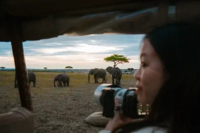 A lady holding professional camera overlooking a classic wildlife photography scene taken from Porini Safari Cottages in Ol Kinyei Conservancy in Kenya. Photo credit Celine & Sacha