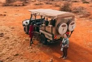 Safari Guide & guest standing by safari vehicle in Selenkay Conservancy in Kenya..Photo credit Vlad Tchompalov