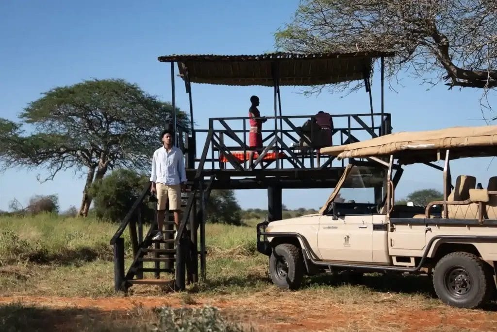 Safari Guide & guest standing on the viewpoint with a safari vehicle in Selenkay Conservancy in Kenya..Photo credit Rameez and Nabel