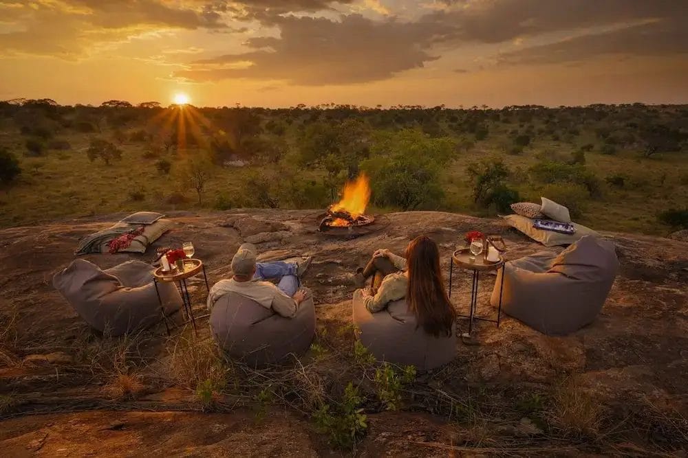 Guests enjoying views with fire and seating area on the rocks at Ilaroi in Tanzania