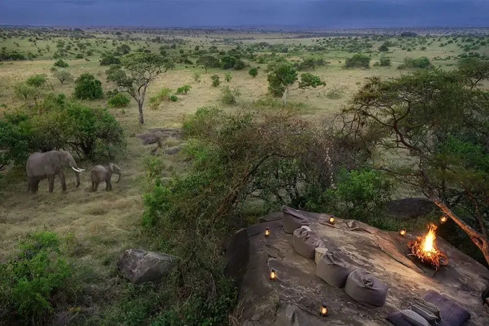 Elephants with fire and seating area on the rocks at Ilaroi in Tanzania
