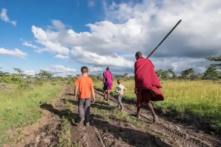 Two children and Maasai Guides walking in Ol Pejeta Conservancy in Kenya - photo credit Axel Fassio